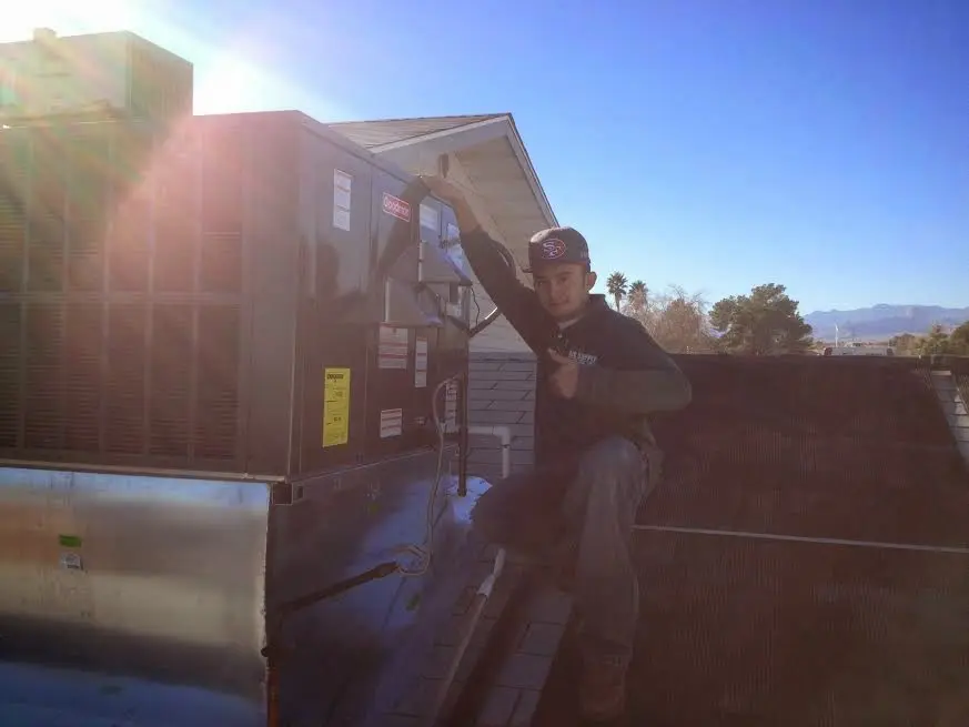 HVAC technician performing Heat Pump Repair on a rooftop unit in Clifton