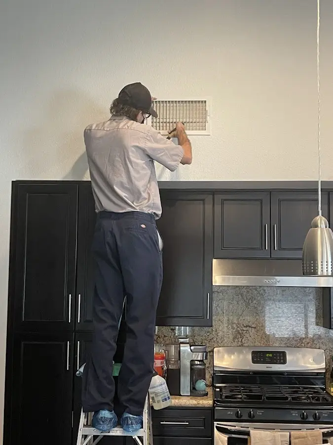 Technician inspecting an air vent during HVAC service in Clifton